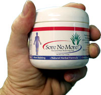Hand holding a jar of Sore No More topical pain relief gel